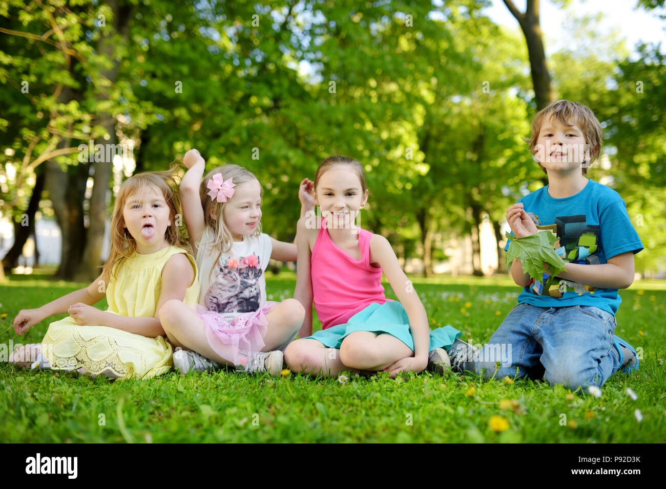 Vier süße kleine Kinder Spaß zusammen auf der Wiese an einem sonnigen Sommertag. Lustige Kinder zusammen hängen im Freien. Aktive Familie Freizeit. Stockfoto