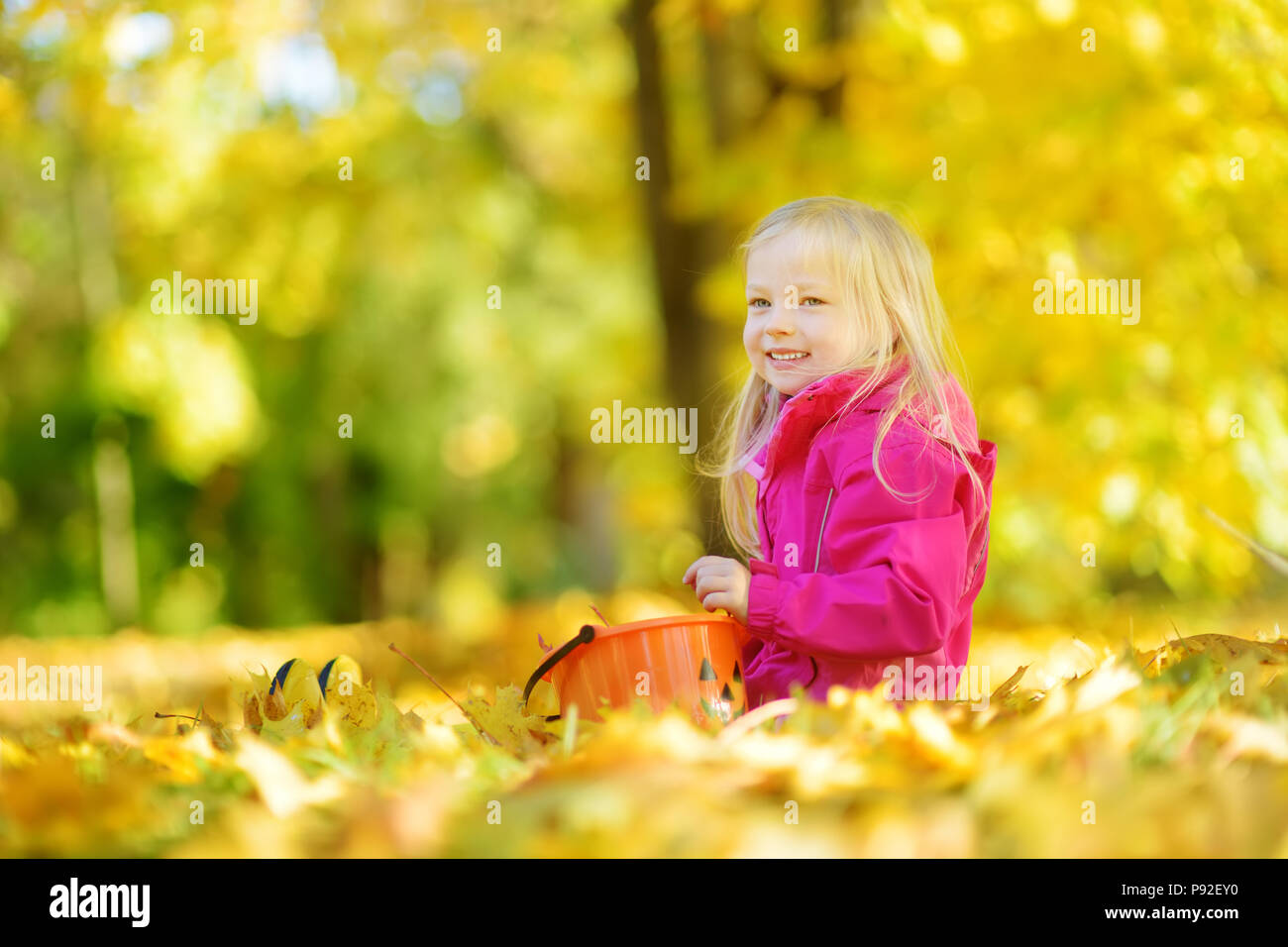 Süße kleine Mädchen Spaß haben auf der wunderschönen Herbsttag. Glückliches Kind spielen im Herbst Park. Kid sammeln Gelb Herbst Laub. Herbst Aktivitäten für Chil Stockfoto