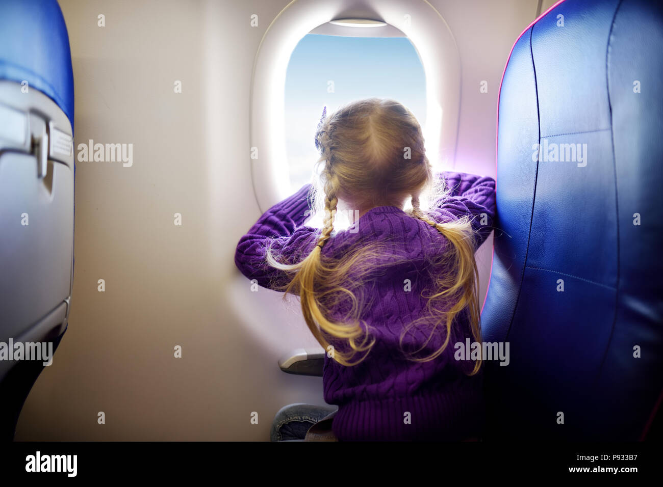 Adorable kleine Mädchen von einem Flugzeug reisen. Kind sitzen durch Flugzeuge Fenster und Außerhalb suchen. Mit kindern unterwegs im Ausland. Stockfoto