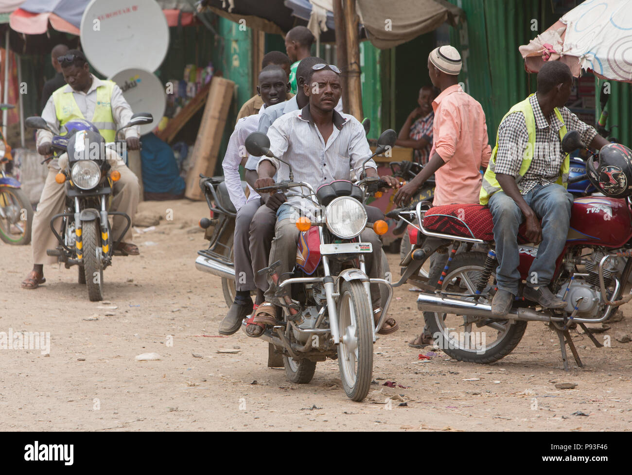 Kakuma, Kenia - Straßenszene mit Menschen und Motorräder. Motorrad Verkehr auf einem langen unbefestigten Straße. Stockfoto