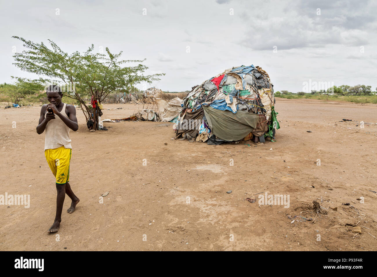 Kakuma, Kenia - Am Rande der Flüchtlingslager Kakuma. Ein junger Mann telefoniert mit seinem Handy. Stockfoto