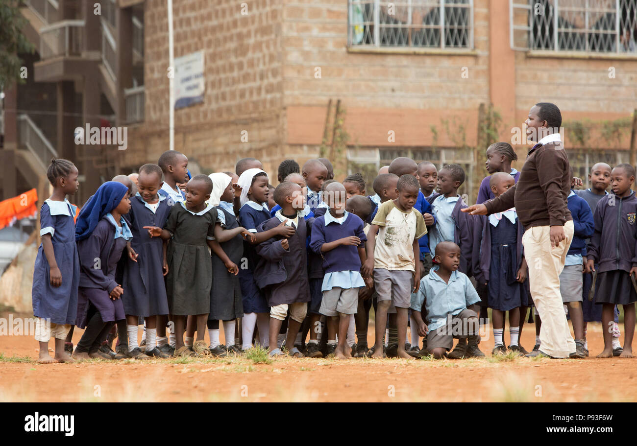 Nairobi, Kenia - Schüler in Schuluniformen aufgereiht vor einem Lehrer im Innenhof des St. John's Community Centre Pumwani. Stockfoto