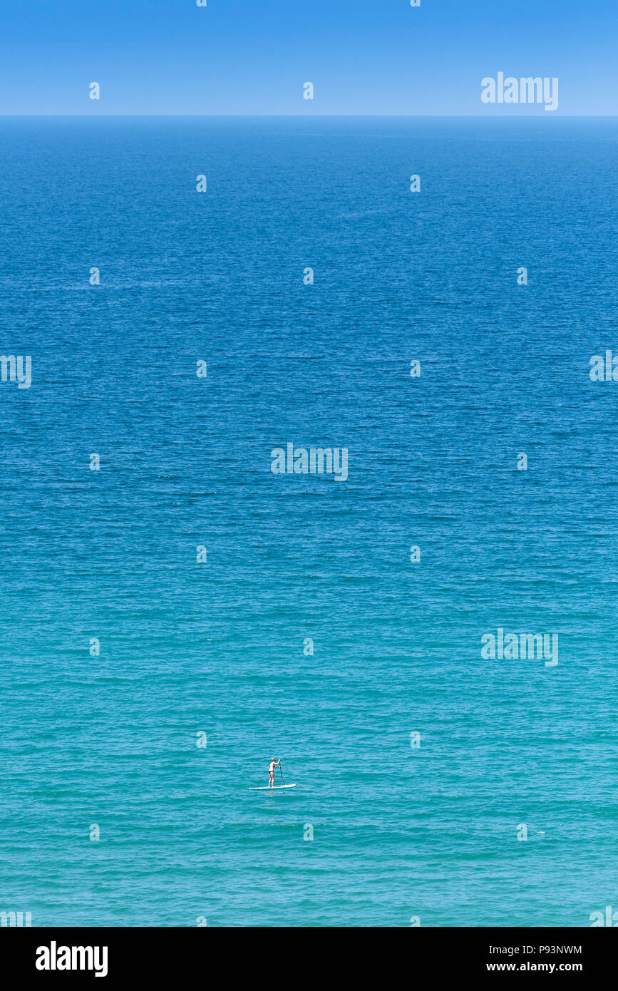 Eine Frau auf einem Paddle Board im Meer. Stockfoto