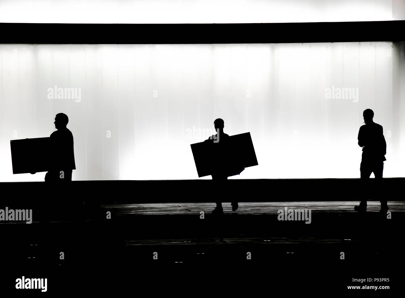 Unscharfe Silhouette von zwei Personen, die jeweils eine große Box Paket Paket- und einem Fuß hinter dem Rauchen vor dem modernen Bürogebäude der Bla Stockfoto