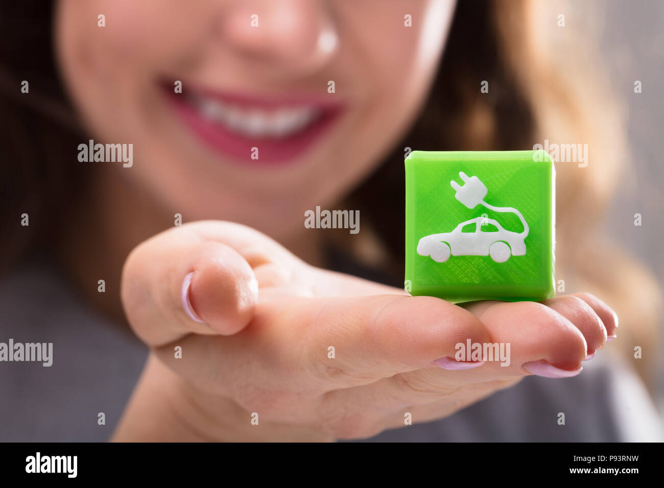Nahaufnahme von einer Frau Hand grün Cubic Block mit elektrischen Auto Symbol Stockfoto