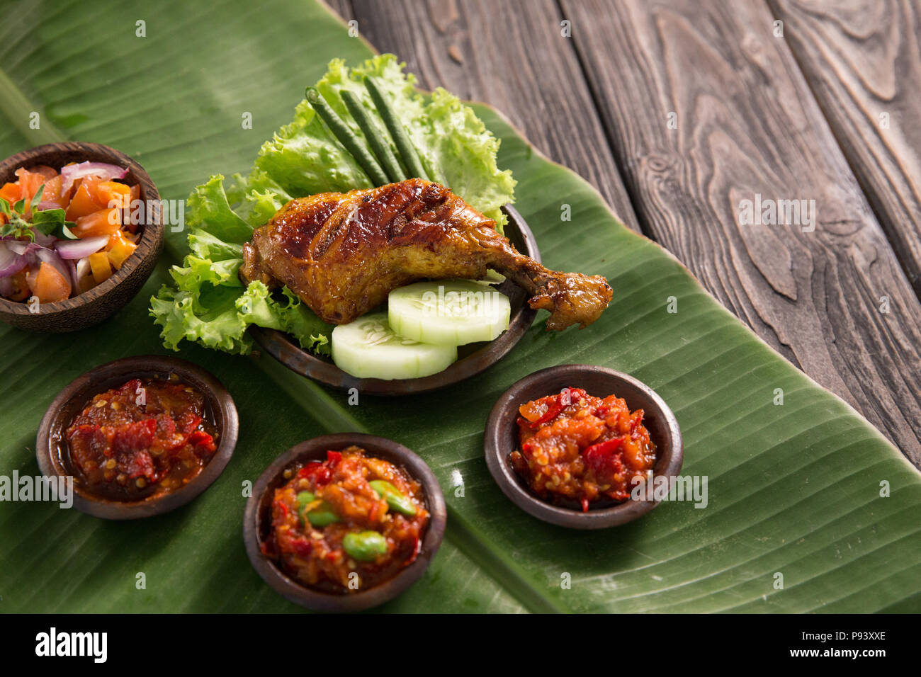 Ayam penyet mit verschiedenen Sambal oder Pikanten Chili Sauce Stockfoto