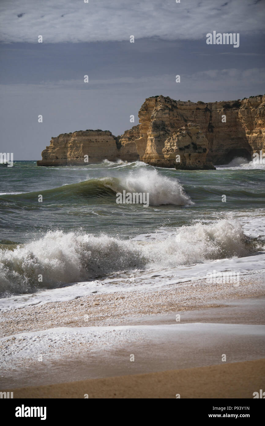 Ruhige Küste der Algarve mit Strand, Meer, Wellen und roten Felsen. Stockfoto