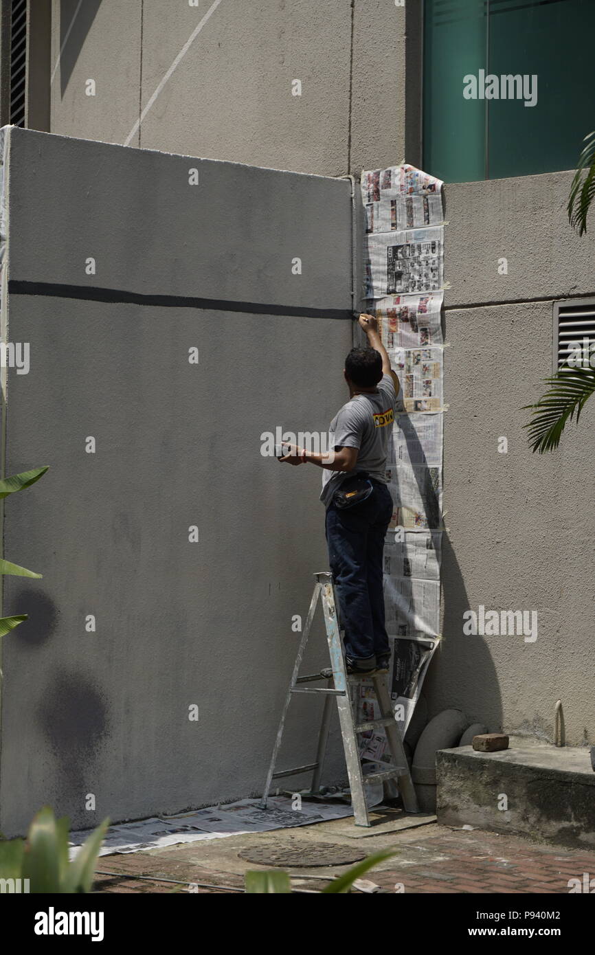 Mann auf Leiter Malerei graue Wand Stockfoto
