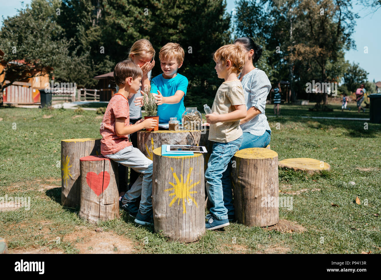 Gruppe junger Schüler in eine Lektion in einem Park. Junge primäre Studenten erkunden Kräuter durch ihre Sinne im Garten. Stockfoto