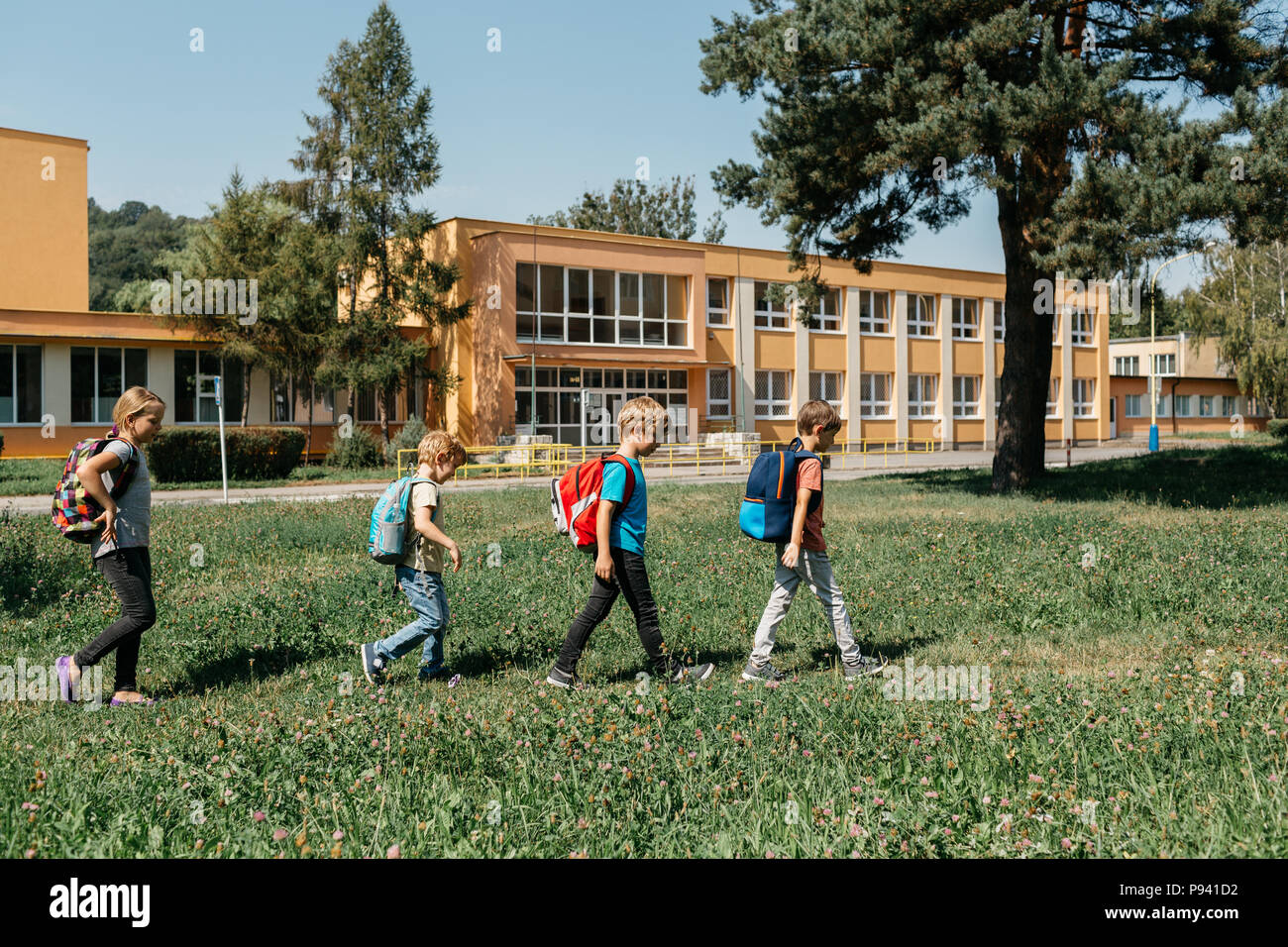 Zurück zu Schule - Kinder eine Schule nach der anderen vorbei. Junge Studenten zu Fuß im Einklang an einem sonnigen Morgen in die Schule. Stockfoto