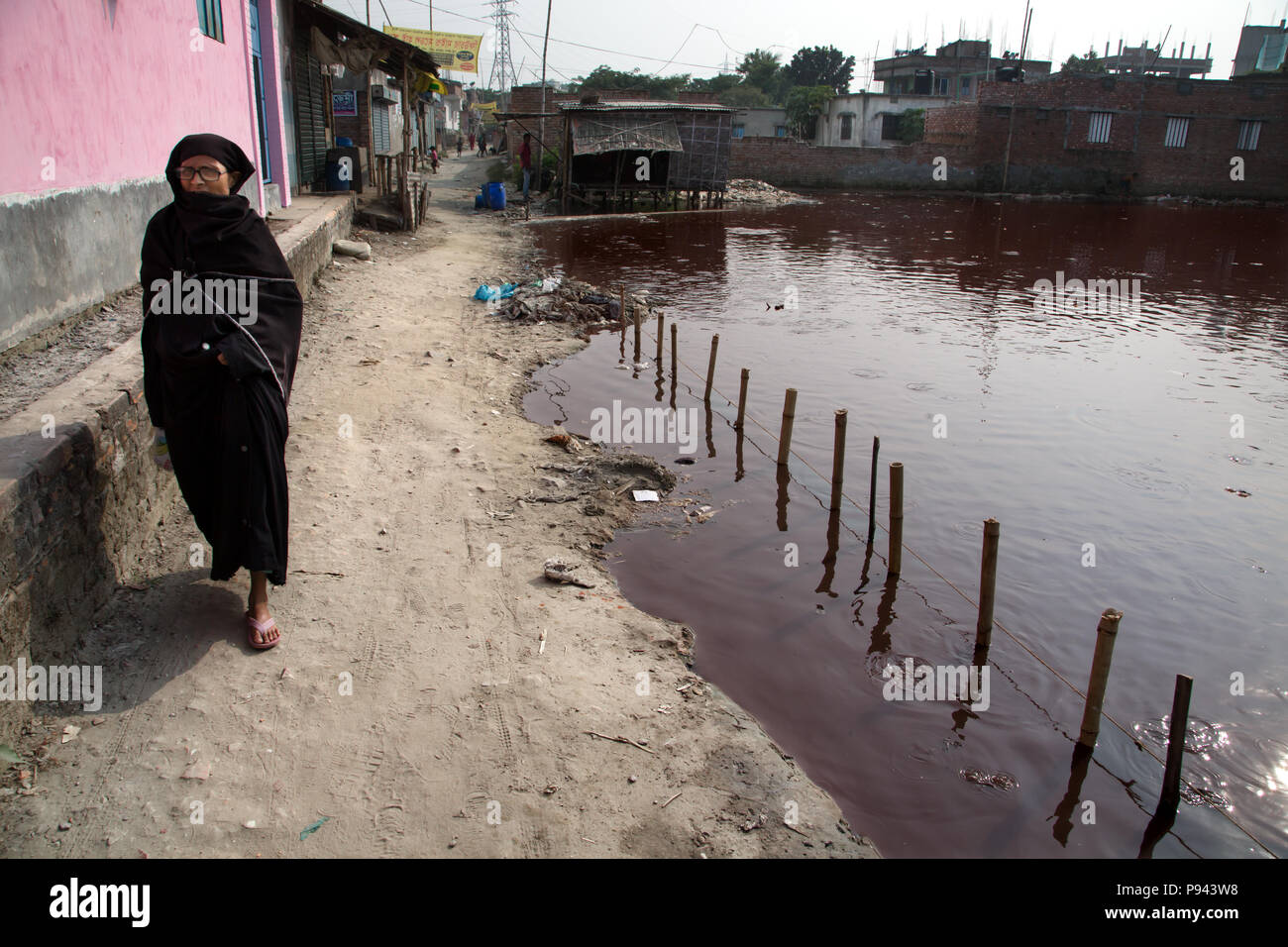 Frau Spaziergänge entlang der Teich voller giftiger Abfälle in Hazaribagh, leder Fabriken/Gerbereien Bezirk, Dhaka, Bangladesch Stockfoto