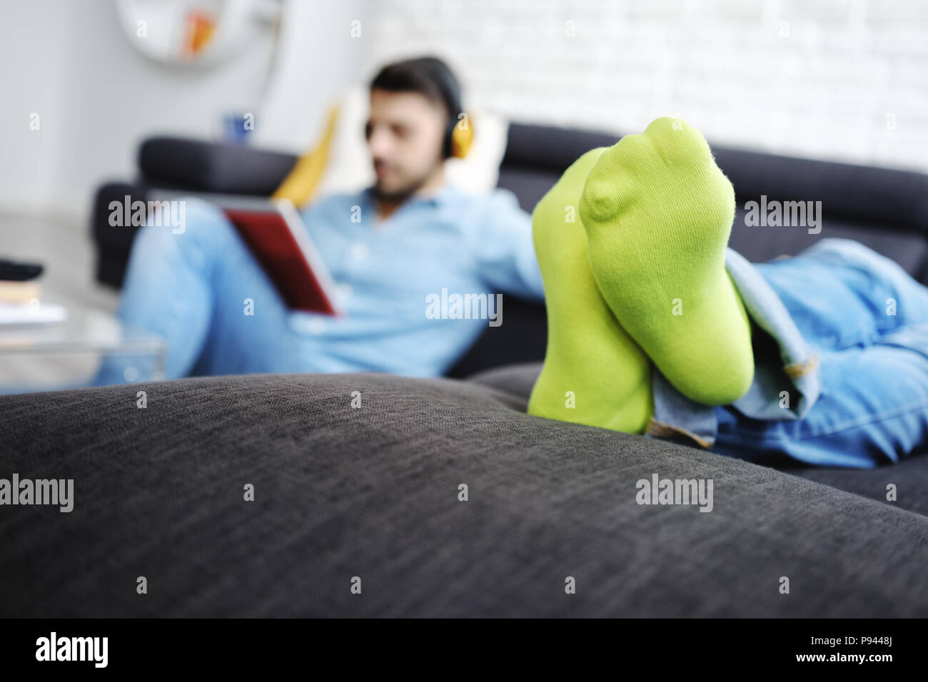 Paar Liegen auf Sofa mit Tablet-PC- und Ohrhörer Stockfoto
