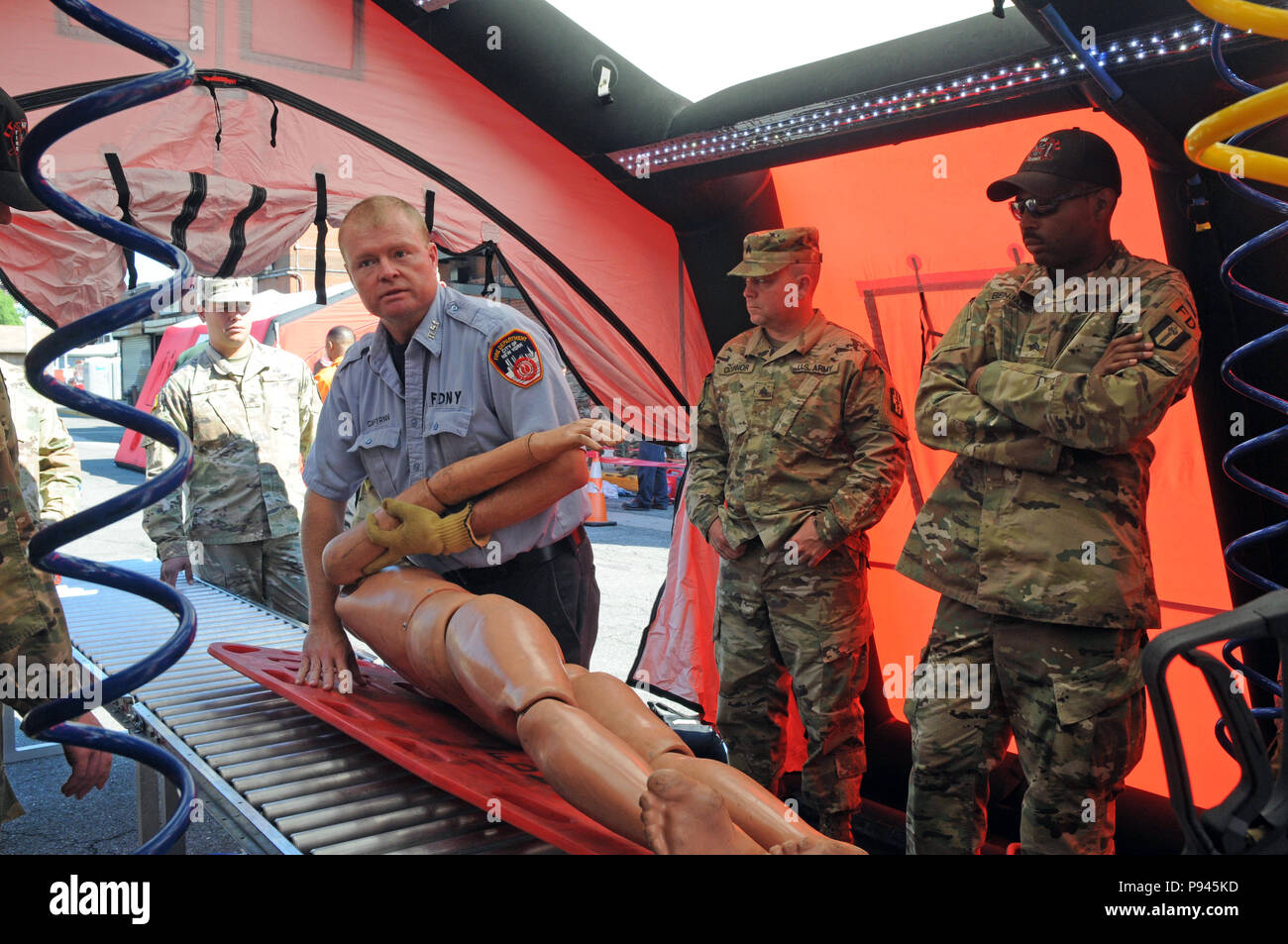 Kapitän Edward Ryan, eine Feuerwehr der Stadt New York (FDNY) Feuerwehrmann, zeigt zu den U.S. Army Reserve Soldaten, einschließlich Sgt. O'Connor, Abteilung 8, 328 Combat Support Hospital, Links, und Sgt. Jason Benjamin, 468Th Engineer Detachment, 368 Techniker Bataillon, 302d Manövrieren Enhancement Brigade, 412 Theater Ingenieur Befehl, wie die Fdny interessiert sich für die ambulante Opfer an der New York City Feuerwehr (FDNY) Brand Academy auf Randalls Island in New York City, New York, 9. Juli 2018. FDNY mit US-Armee Northern Command (NORTHCOM) leitet die Ausbildung Als gemeinsame Ausübung simulati Stockfoto