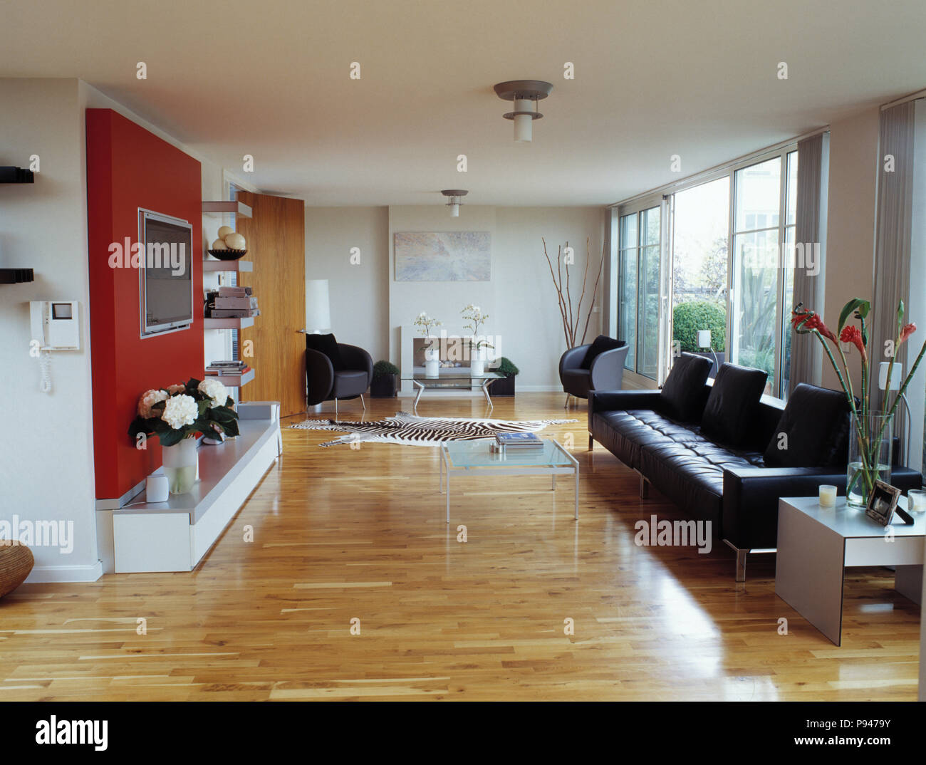 Schwarzes Ledersofa und Holzböden in Großes modernes weißes Wohnzimmer mit  Terrassentüren Stockfotografie - Alamy