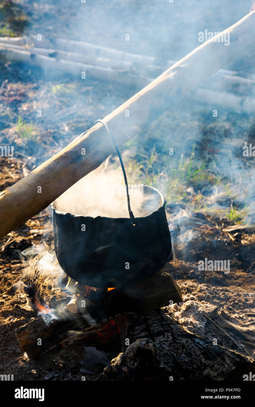 Alte Schule weg, Kaffee im Freien. Dampf und Rauch. schwarze Kessel hängen auf dem Baumstamm über dem Kamin. wunderbar schmeckt der Sommer und h Stockfoto