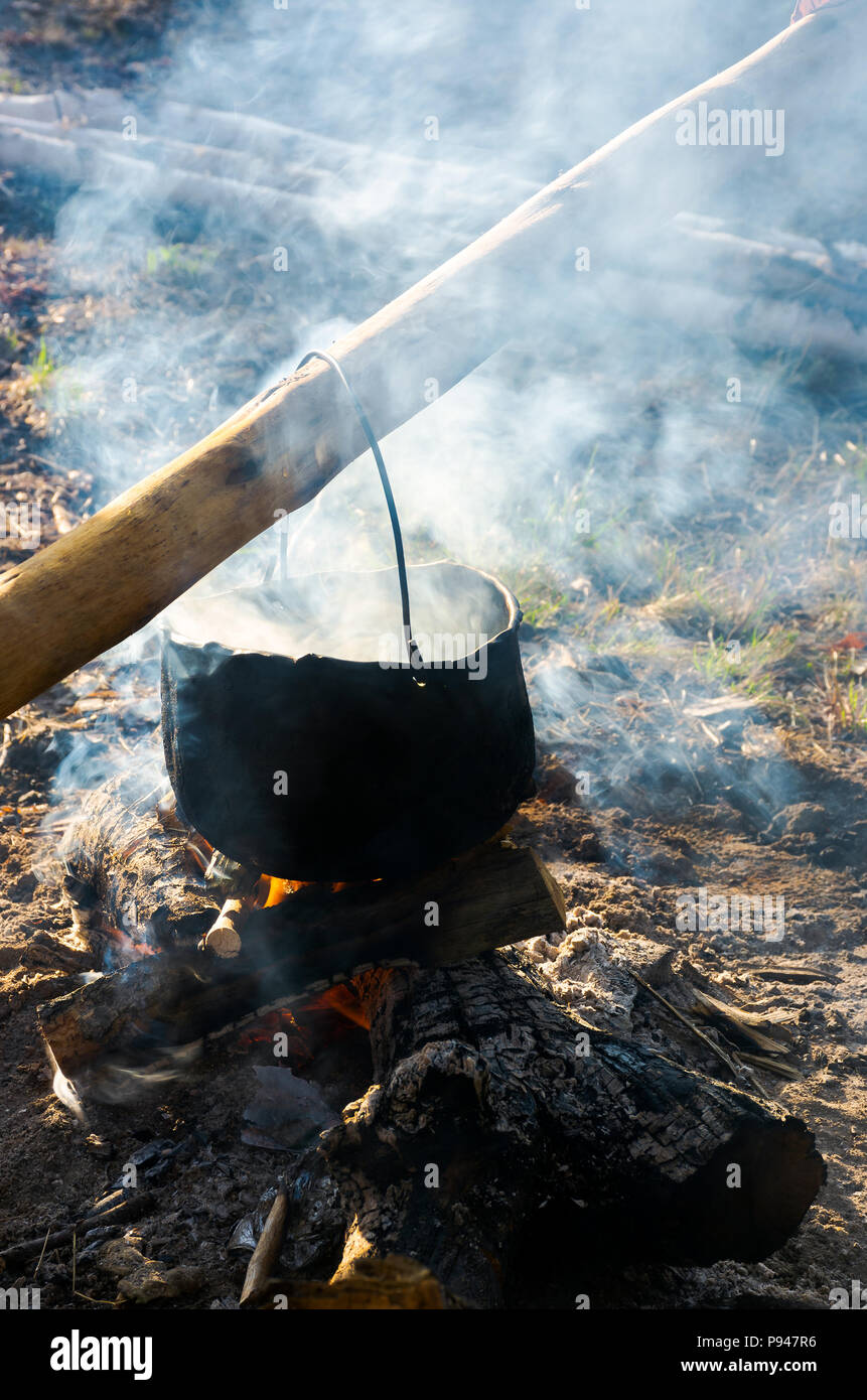 Alte Schule weg, Kaffee im Freien. Dampf und Rauch. schwarze Kessel hängen auf dem Baumstamm über dem Kamin. wunderbar schmeckt der Sommer und h Stockfoto