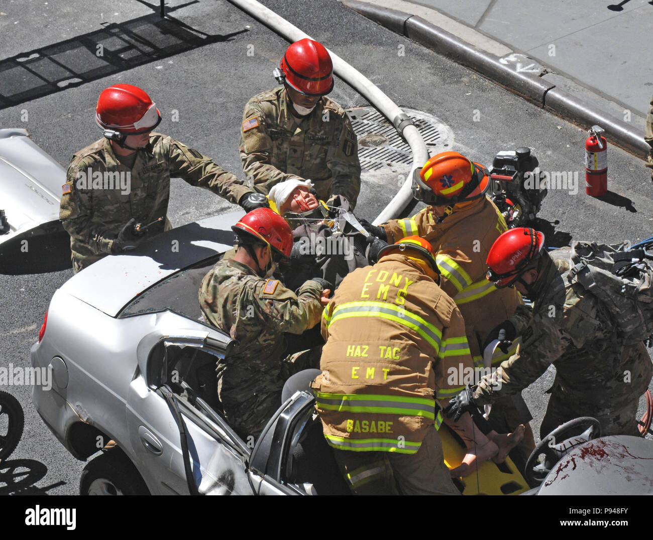 Us-Armee finden Sgt. Mathew Annis, Oben links, und Spc Aldrich Cushnie der 287 Engineer Detachment (löschteam), 368 Techniker Bataillon, 302d Manöver Verbesserung Brigade, 412 Theater Ingenieur Befehl, in Danvers, Massachusetts, sind von Victor Basabe und Edwin Hernandez unterstützt, Notfallmediziner, Haz-Mat Operationen, Feuerwehr der Stadt New York (FDNY), da sie ein "Opfer" von einem Autounfall während der New York City Gemeinsamen chemischen, biologischen, radiologischen oder nuklearen Ereignis Reaktion Demonstration am Times Square Church in New York City, 10. Juli Stockfoto