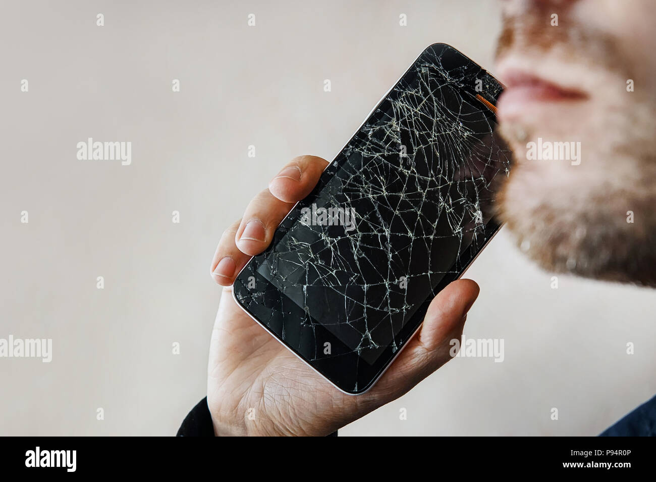 Der Kerl ist ein Gespräch mit einem defekten Bildschirm. BlackBerry-Smartphone mit zersprungenem Glas in der Hand eines Mannes. Kopieren Sie Raum. Copyspace. Stockfoto
