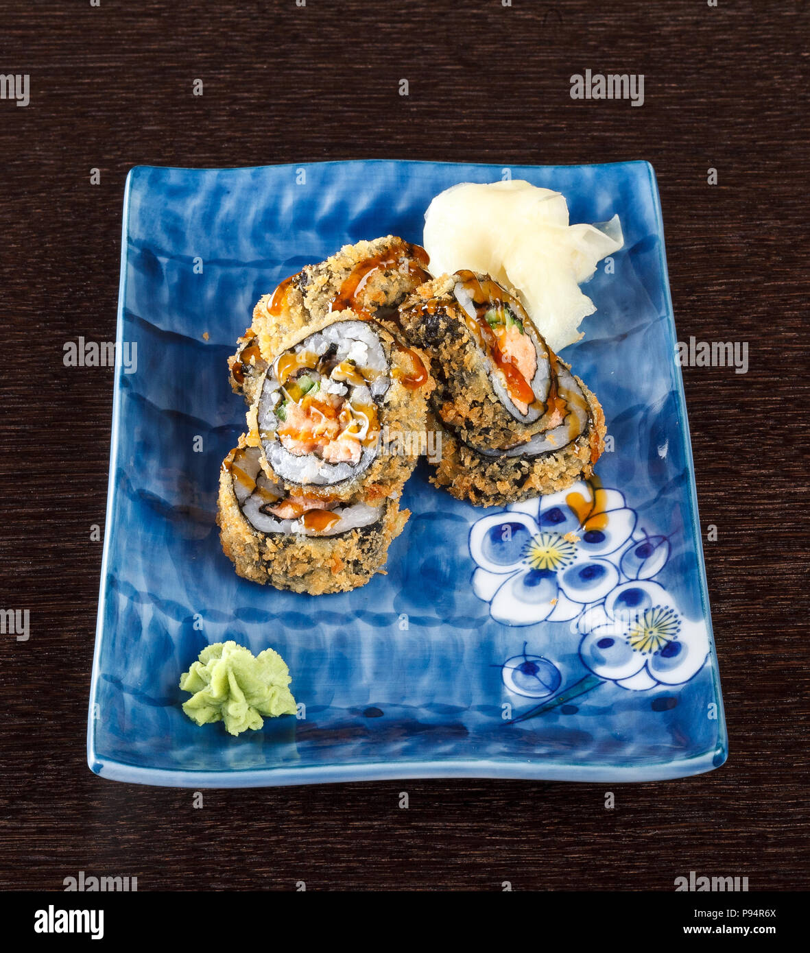 Heißes gebratenes Sushi rollen auf einem Teller mit Lachs und Gurke auf Holztisch. Stockfoto