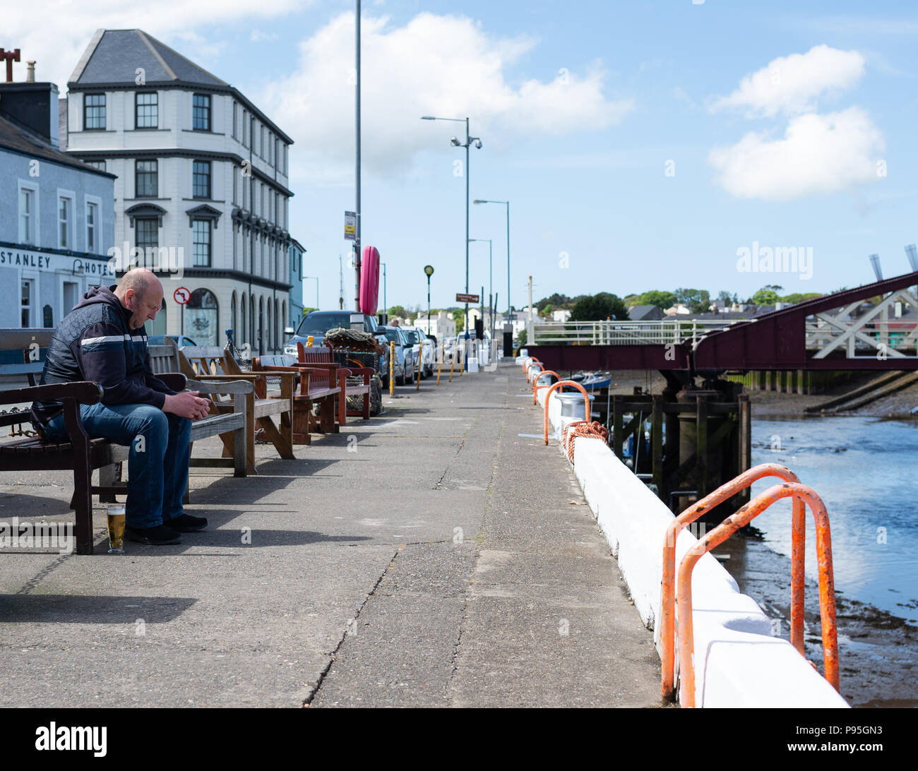 Mann sitzt auf einer Bank, Ramsey Hafen Stockfoto