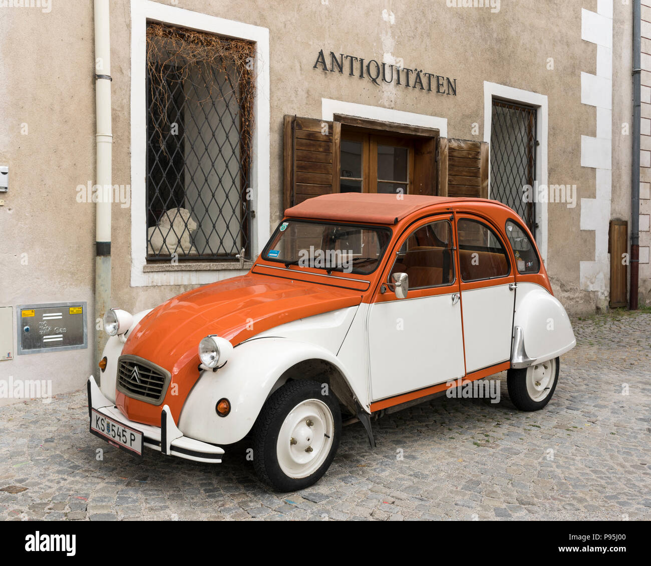 Eine klassische Citroën 2CV mit Orange und Weiß Verkleidung unter der ein Antiquitätengeschäft Zeichen in Stein an der Donau, Niederösterreich Stockfoto