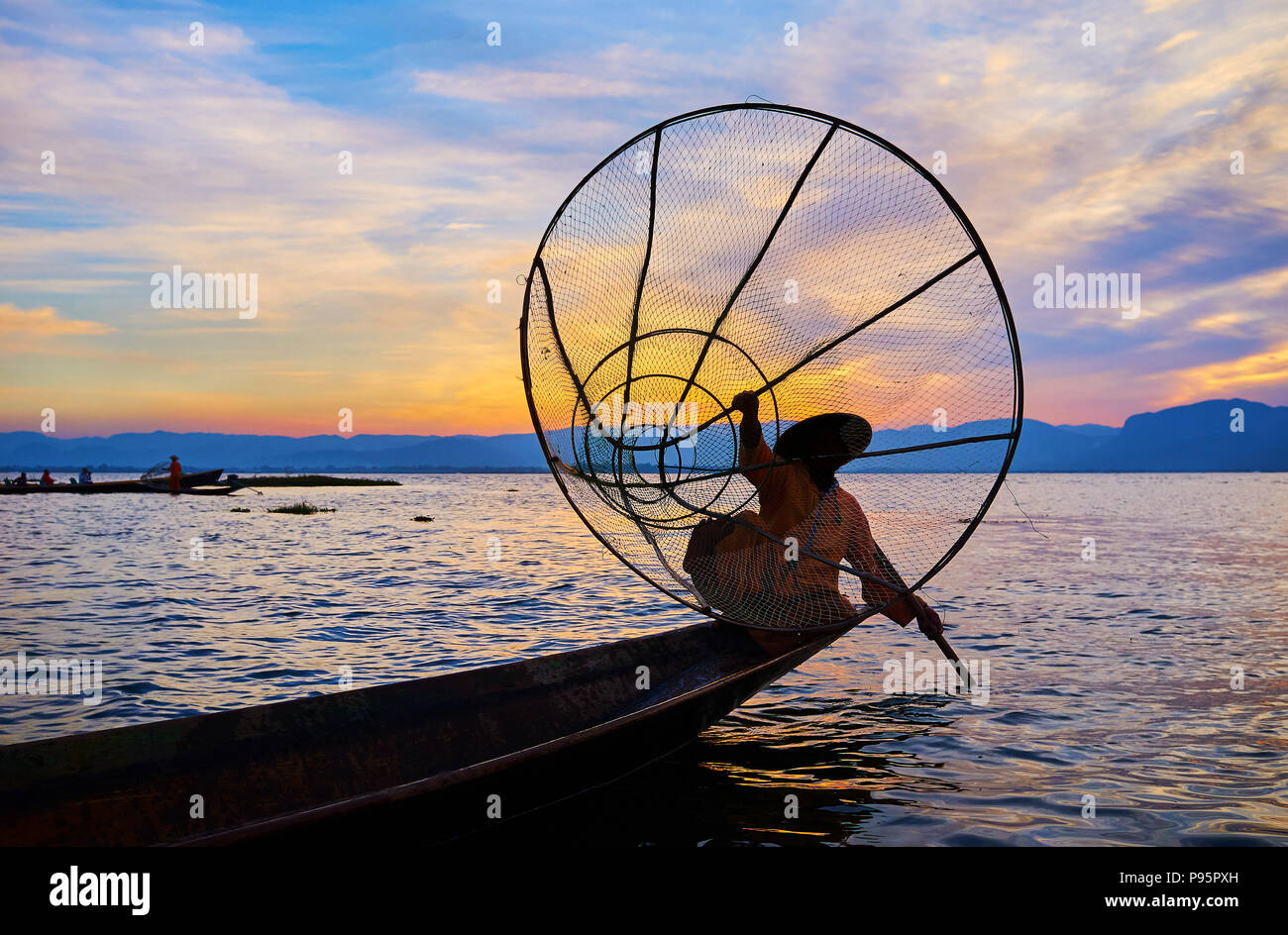 Die burmesische Fischer hält seine konische Net, Standortwahl am Rande des mit dem Kajak Paddel in der anderen Hand am Inle See, Intha, Myanmar. Stockfoto