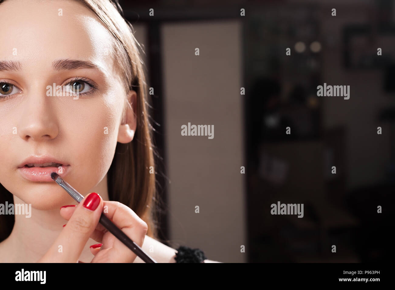 Make-up-Artist der Anwendung eine Lippe auf einem jugendlich Glanz Stockfoto