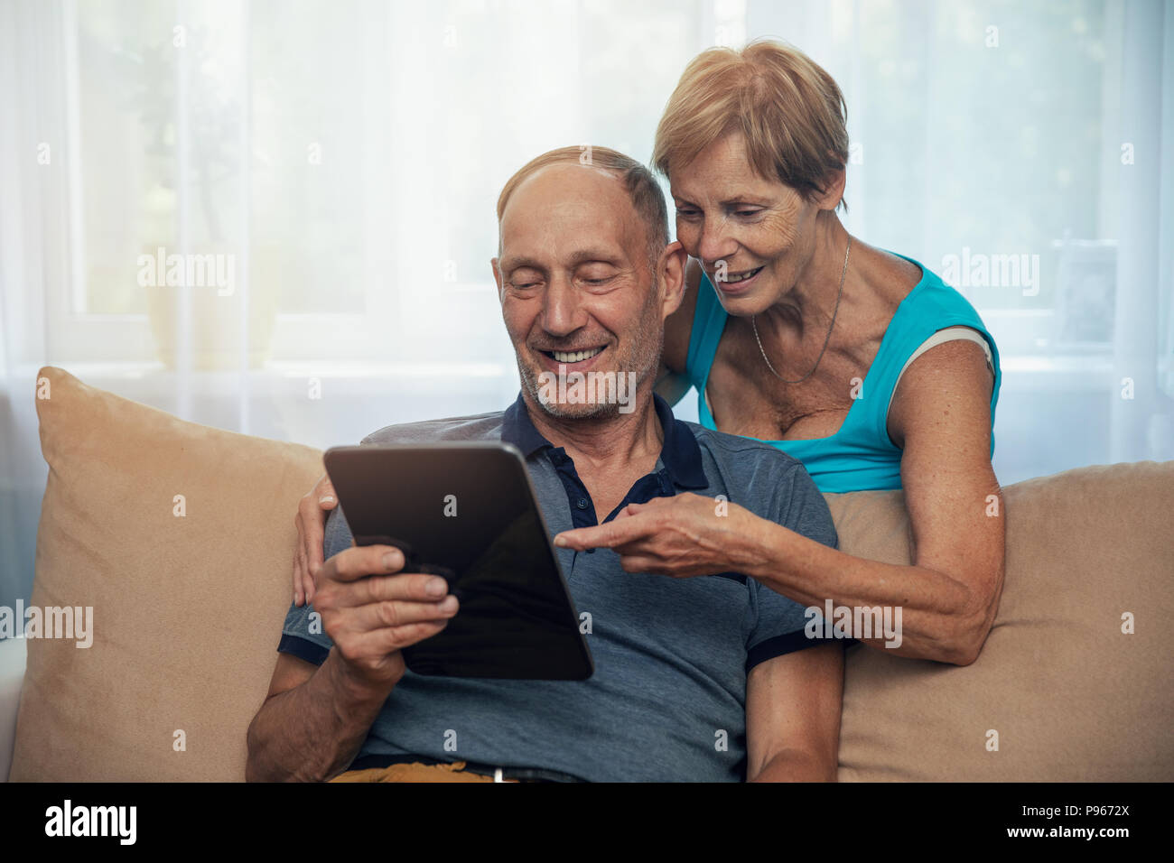 Gerne älteres Paar mit digitalen Tablette zu Hause Stockfoto