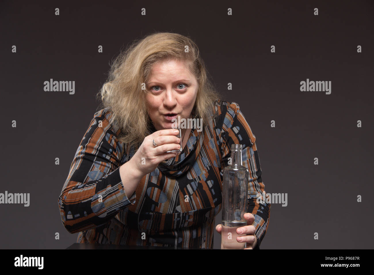 Einsame reife fette Frau alkoholische Getränke Wodka aus Gläsern und  Weingläser und Snack Gurke und getrockneten Fisch Stockfotografie - Alamy