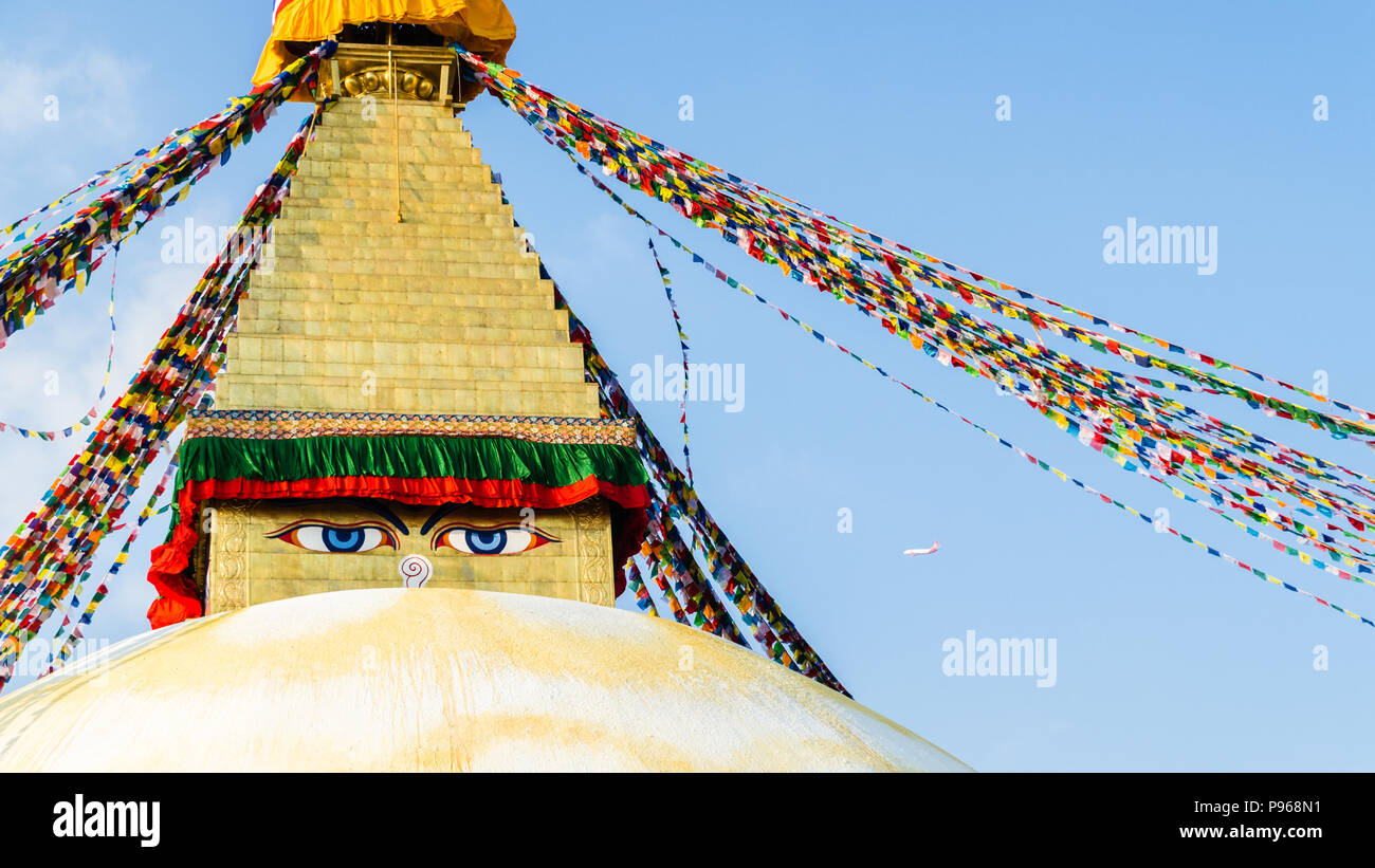 Flugzeug neben Buddha Eyes, weißen Stupa und den Gebetsfahnen in Boudhanath oder Buddha Stupa Stockfoto