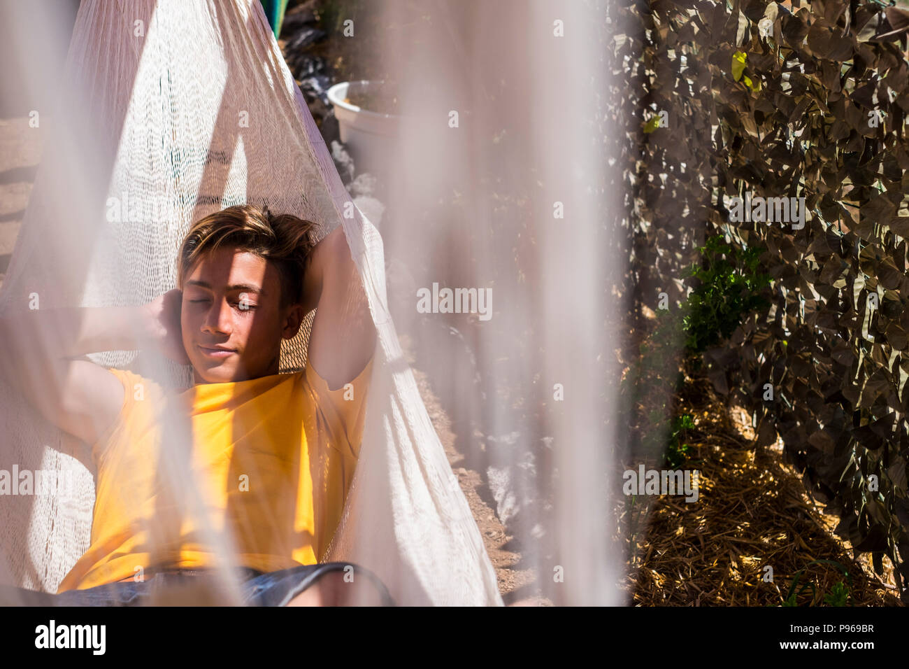 Schönen kaukasischen Jungen Aufenthalt und Erholung auf einer Hängematte im Freien in der Natur. ernsten Ausdruck Gesicht für Teenager Zeit und Alter. Stockfoto