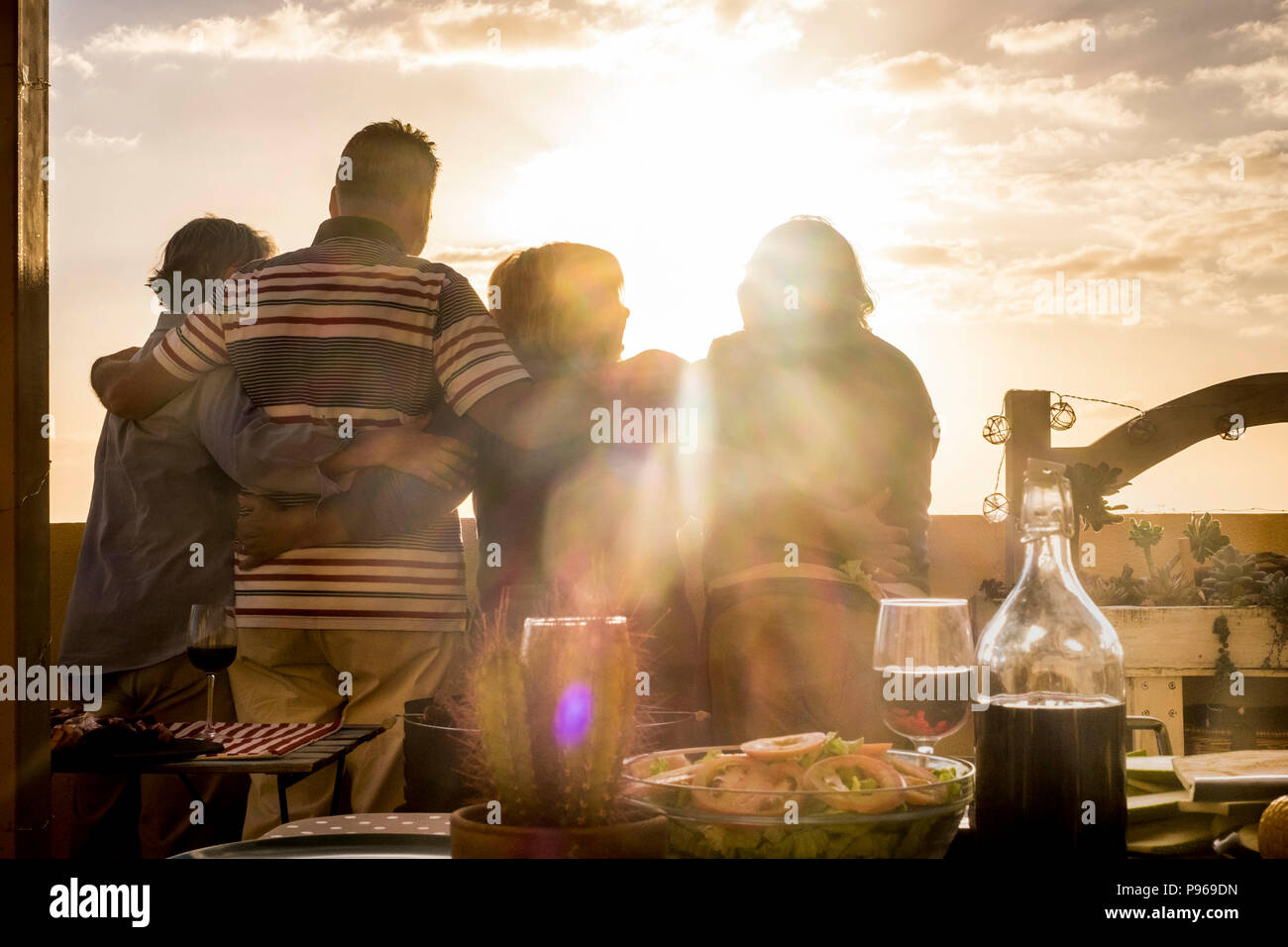 Menschen Gruppe von älteren Freunden Umarmung und zusammen großartig Anzeigen der golde Sonnenuntergang von der Dachterrasse. Wohnen immer in Urlaub und Ruhestand happi Stockfoto