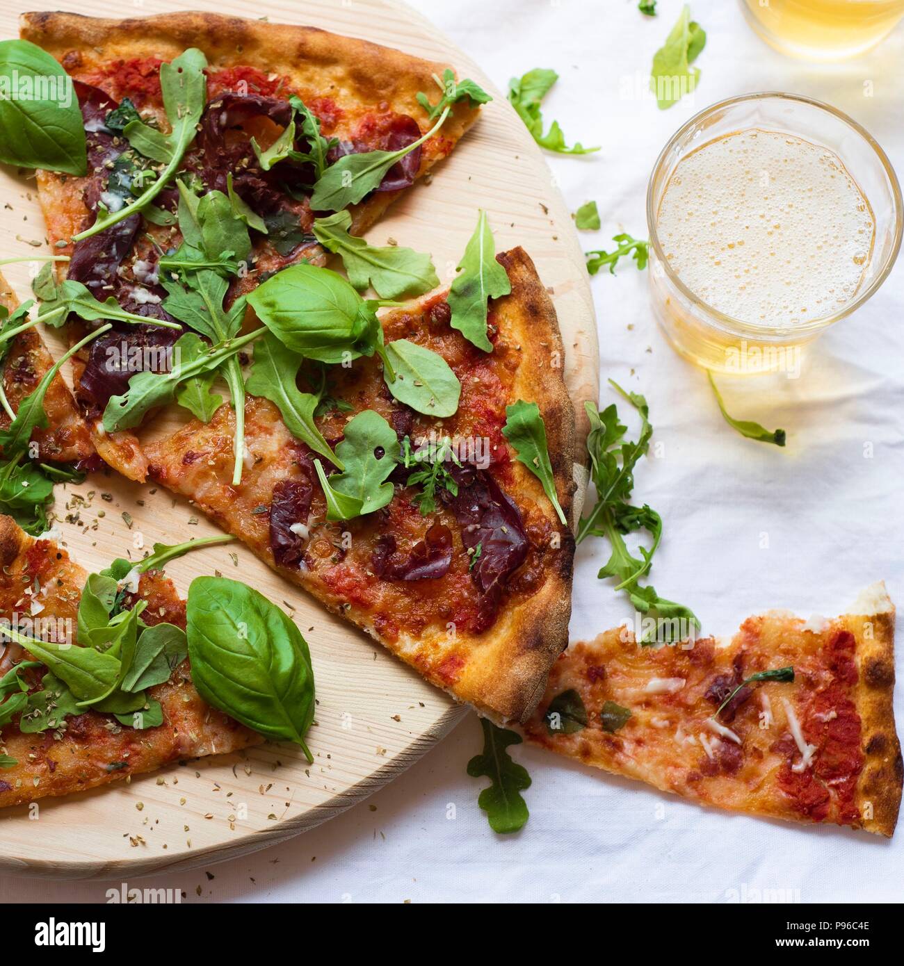 Flach hausgemachte leckere Pizza und Bier auf Holzbrett über weiße Tischdecke Hintergrund Stockfoto