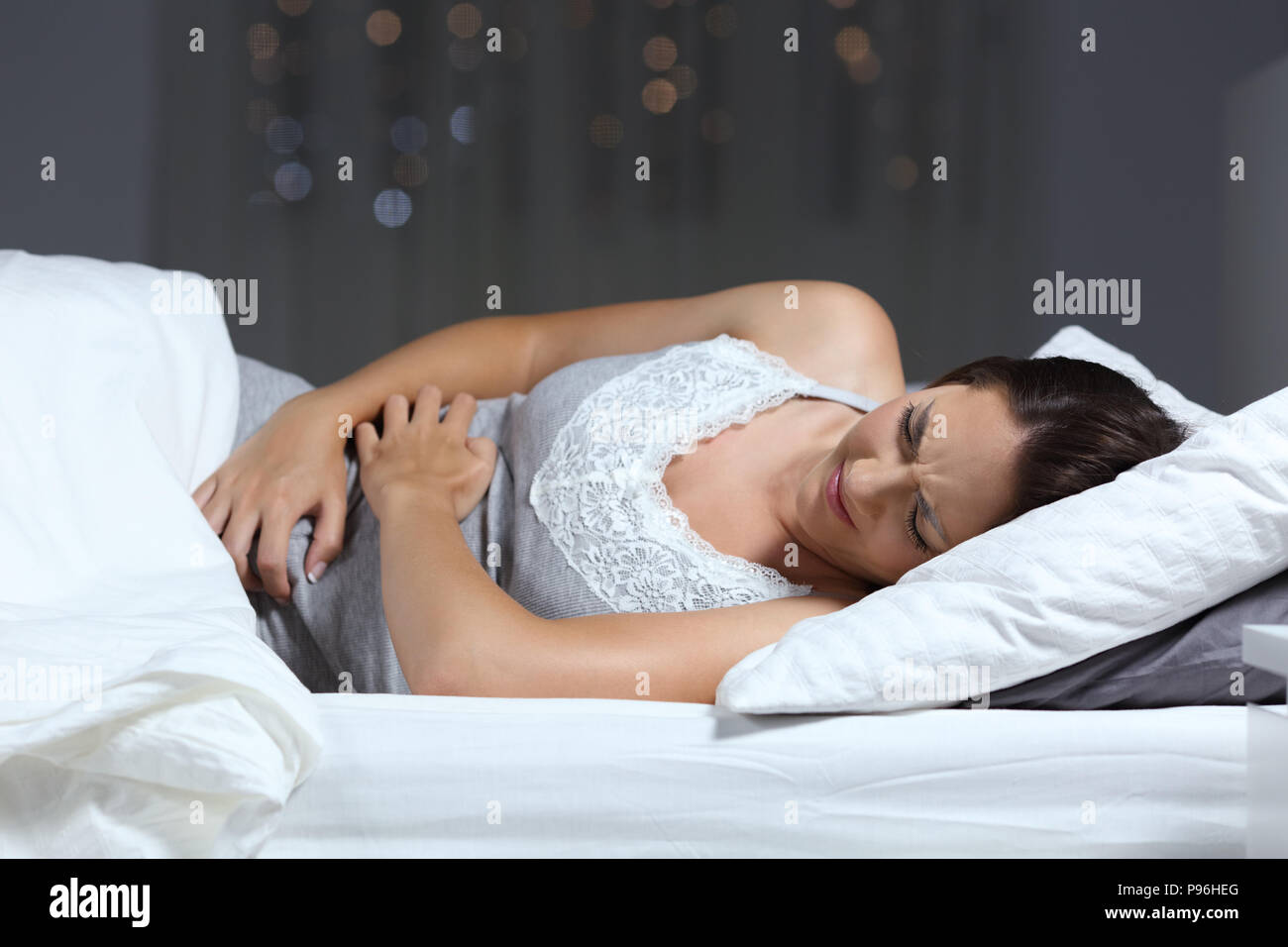 Frau mit Bauchschmerzen in der Nacht auf dem Bett zu Hause liegen Stockfoto