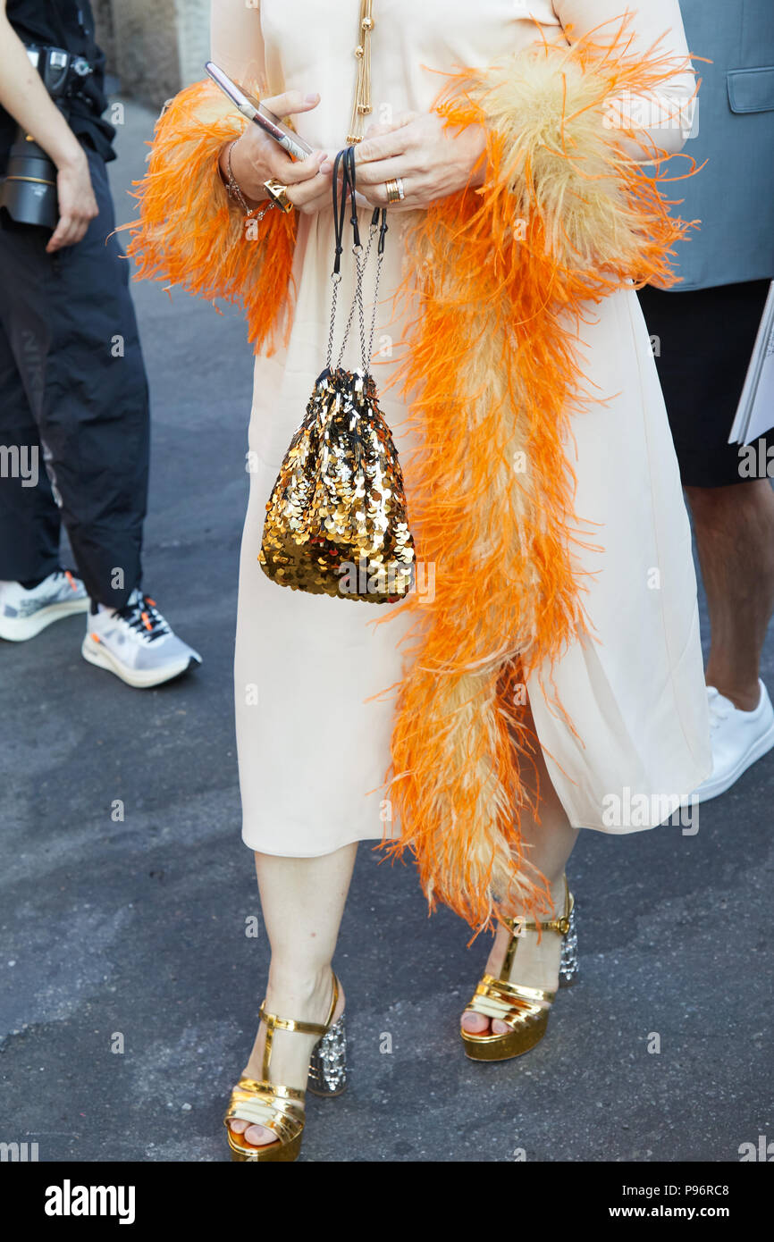 Mailand - Juni 17: Frau mit Telefon und goldene Pailletten Tasche und orange Federn Manschetten an den weißen Kleid vor Prada fashion show, Mailand Fashion Week str Stockfoto