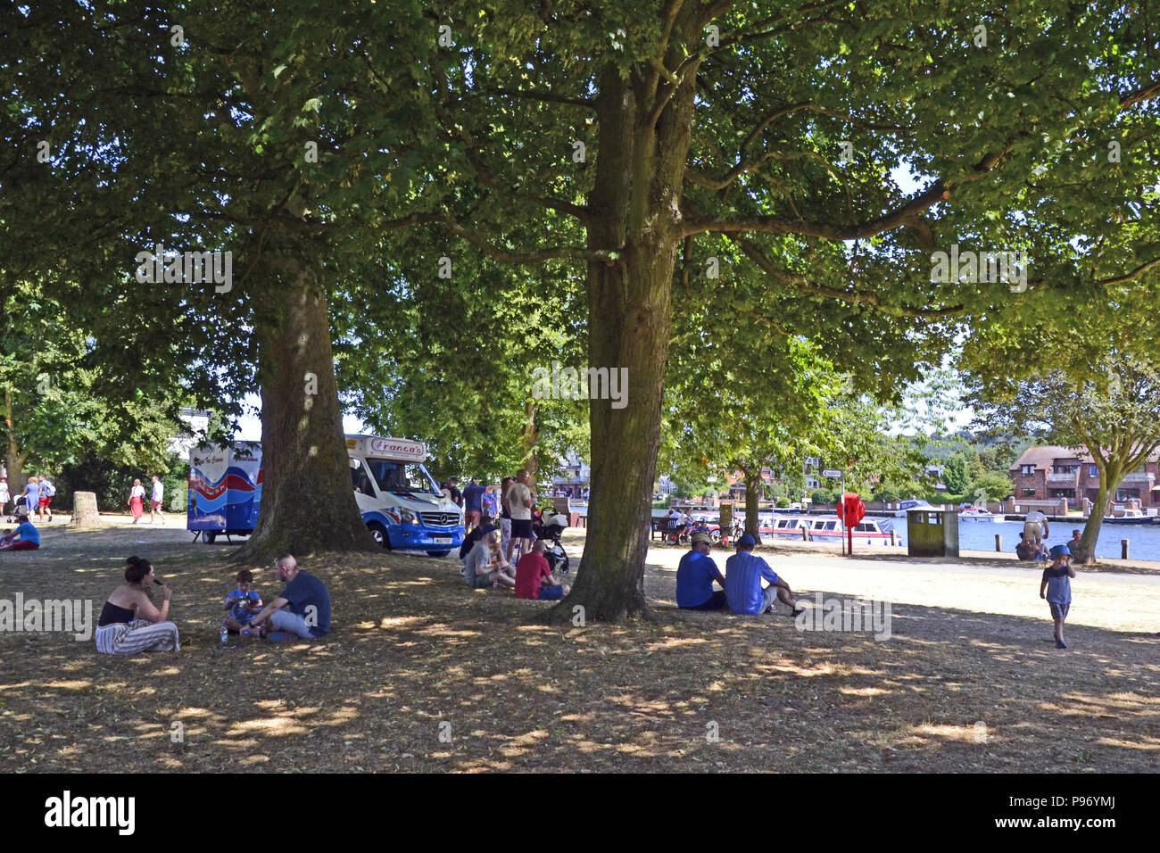 Menschen sitzen unter einem Baum an einem heißen Tag neben der Themse in Marlow, Buckinghamshire, England, Großbritannien Stockfoto