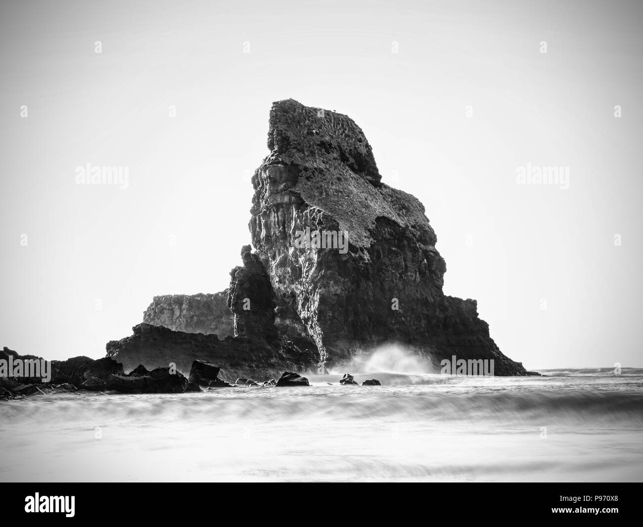 Scharfen Silhouetten und Geröll hervorstehen von glatten Meer. Blau Atmosphäre in windstillen Abend am Meer. Stockfoto