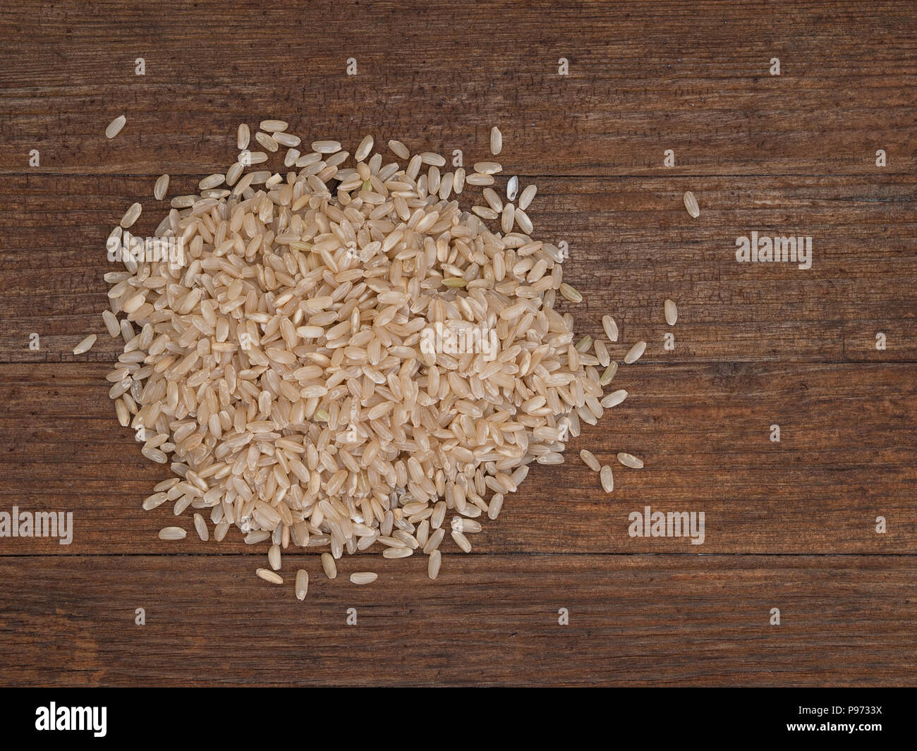 Langkörniger brauner Reis auf rustikalen Holzbrett. Organische. Mit Copyspace. Stockfoto