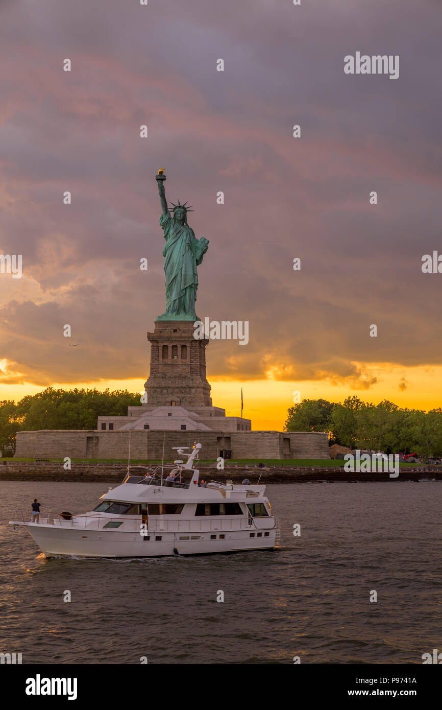 Sonnenuntergang Blick auf die Freiheitsstatue mit Segelboot vorbei in den Hafen von New York Stockfoto