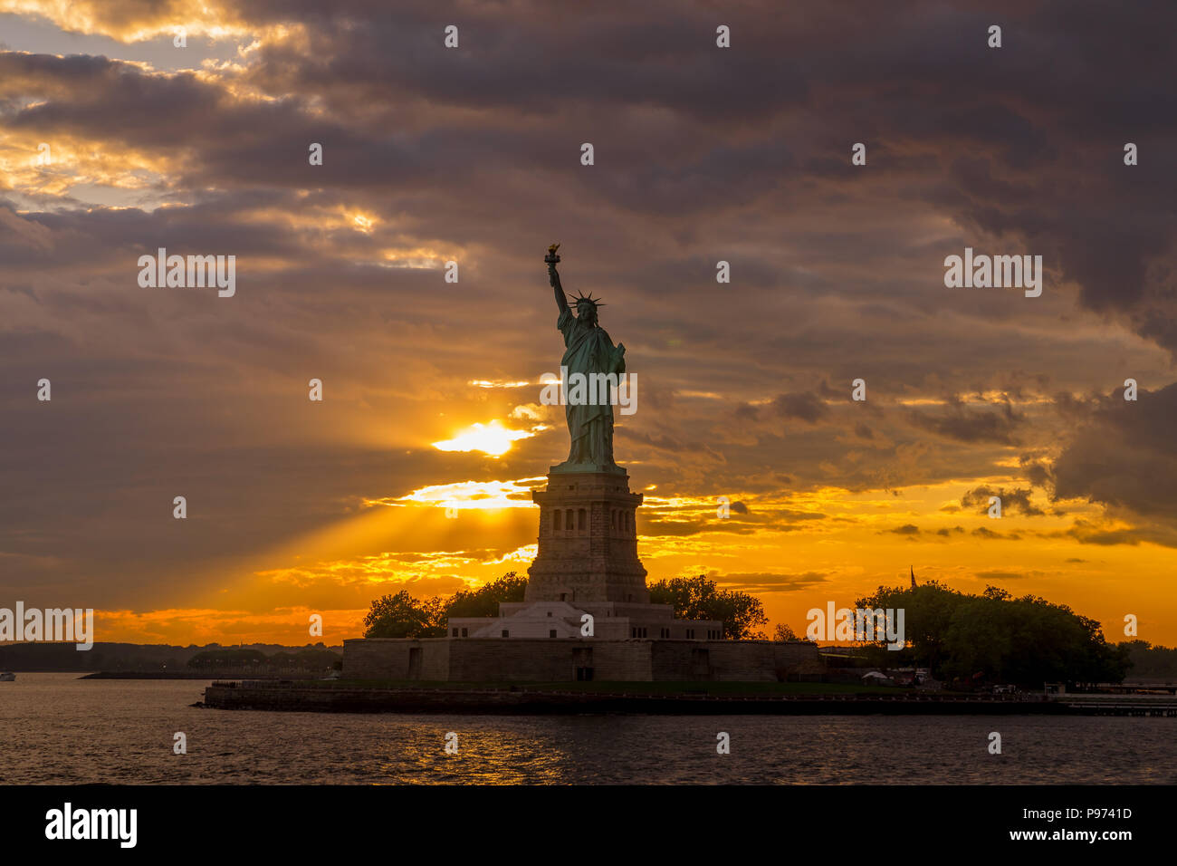 Schönen Sonnenuntergang leuchtet die Freiheitsstatue im Hafen von New York Stockfoto