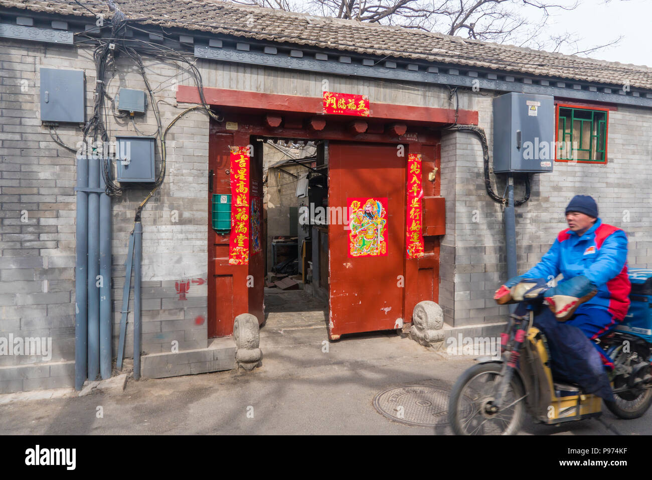 Mann, ein Motorrad in einem Hutong in Peking. Hutongs sind enge Gassen in der traditionellen chinesischen Wohngebiete und ein Stockfoto