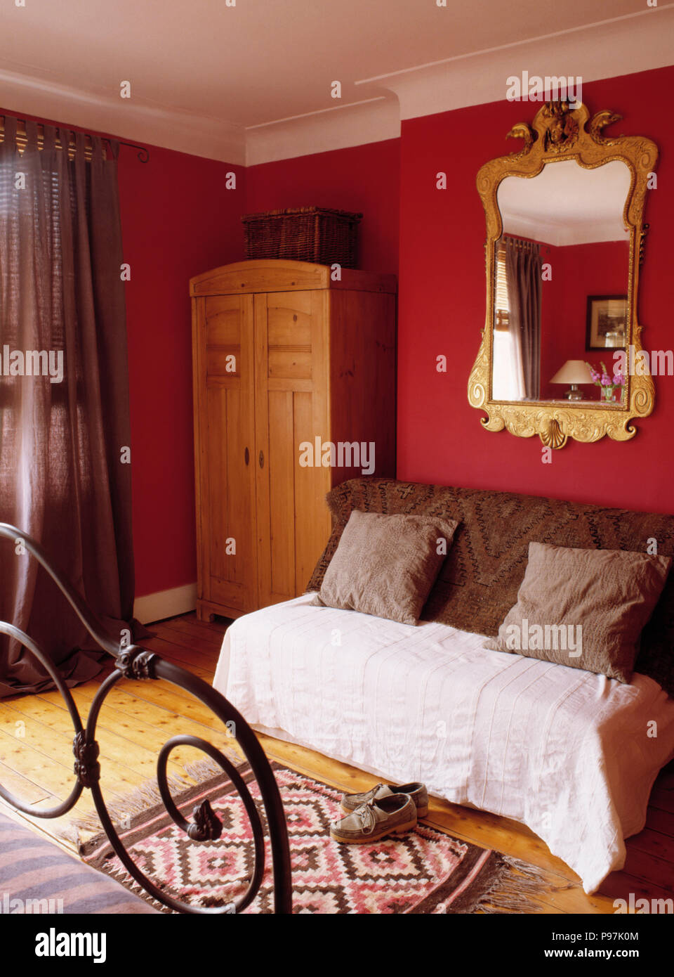 Reich verzierten vergoldeten Spiegel über Couch mit braun Kissen werfen in  Rot und Creme Schlafzimmer mit Schrank aus Kiefernholz Stockfotografie -  Alamy