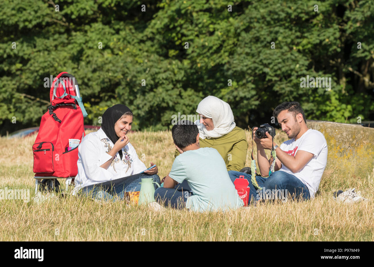 Asiatische Familie essen (mit einem Picknick, Picknick) außerhalb in der britischen Landschaft in East Sussex, England, Großbritannien. Jeden Tag. Stockfoto