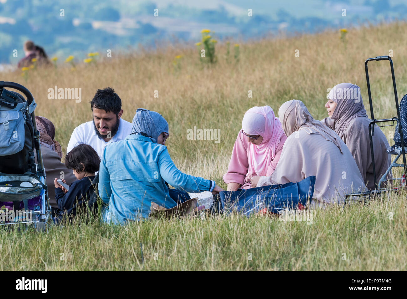 Asiatische Familie essen (bei einem Picknick, Picknicken) außerhalb der britischen Landschaft in East Sussex, England, UK. Stockfoto