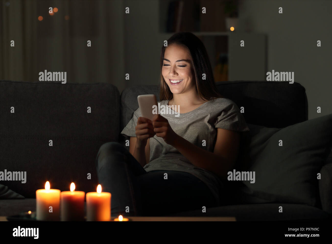 Mädchen Schreiben von Nachrichten über ein Telefon in der Nacht auf einer Couch im Wohnzimmer zu Hause sitzen Stockfoto