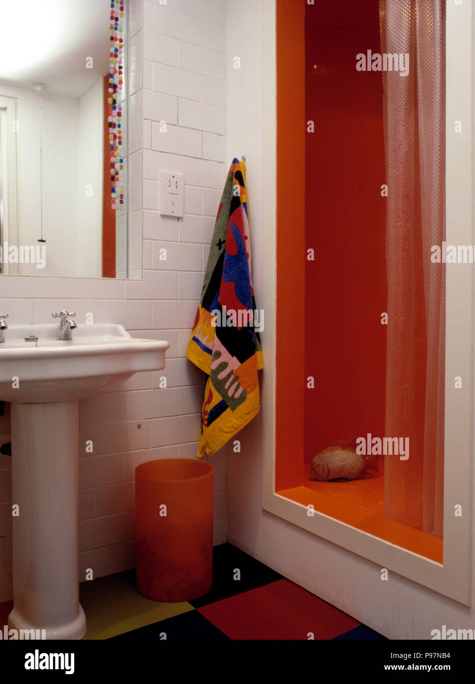 Buntes Handtuch auf weißen Fliesen Wand neben orange Dusche ... Buntes Handtuch auf weißen Fliesen Wand neben orange Dusche ...
