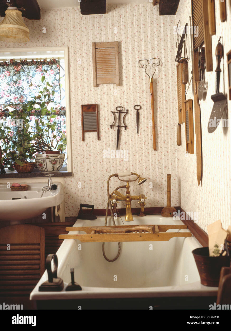 Sammlung von alten Waschbretter und Holz- Utensilien auf Wand über Badewanne mit Holz- bathrack im Land Bad Stockfoto