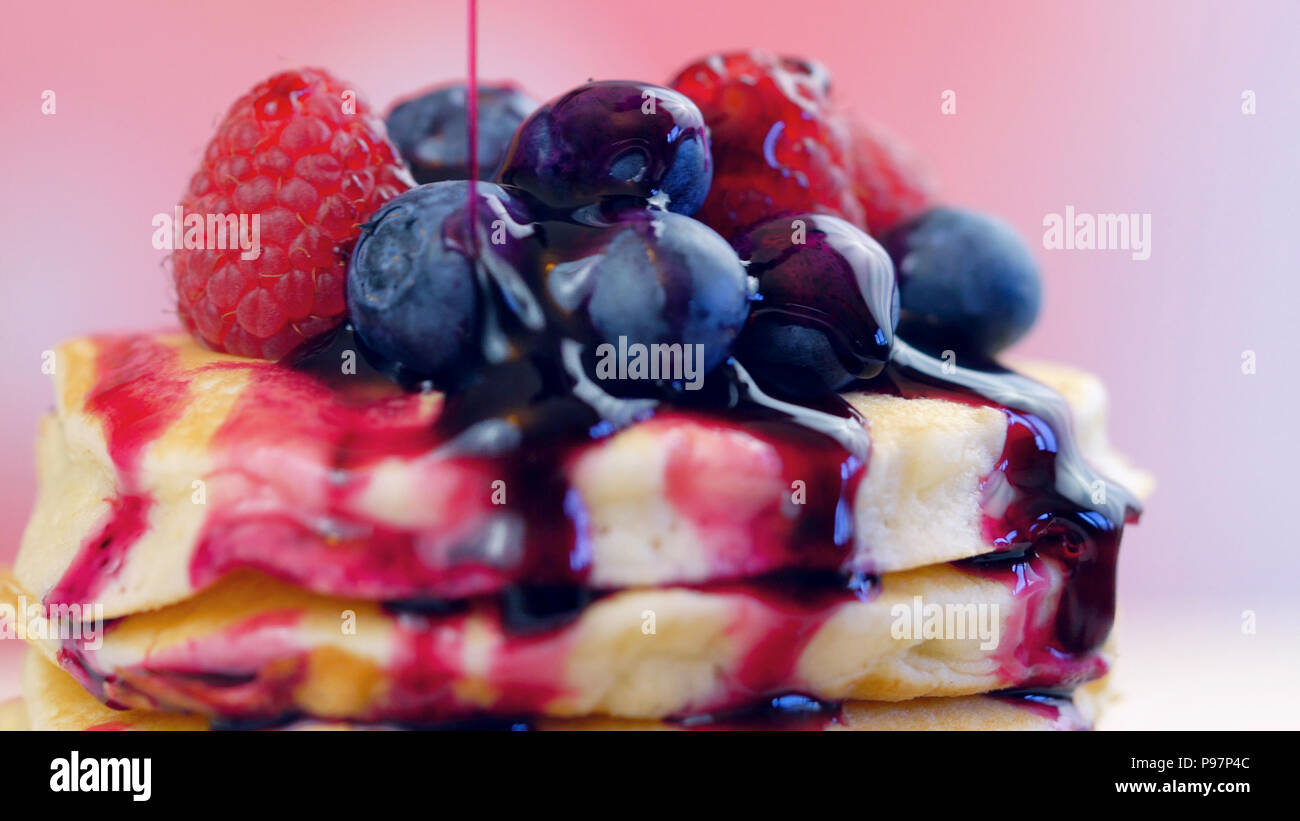 Der Pfannkuchen mit Himbeeren, Heidelbeeren Stack und mit blueberry Ahornsirup beträufelt, Makro Nahaufnahme. Stockfoto