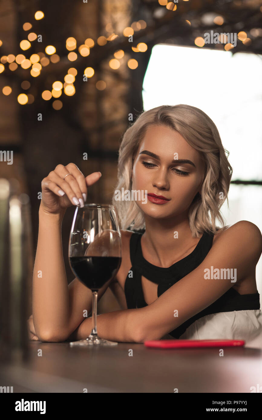 Schöne blonde Frau, die ihr Glas Wein betrachten Stockfotografie - Alamy