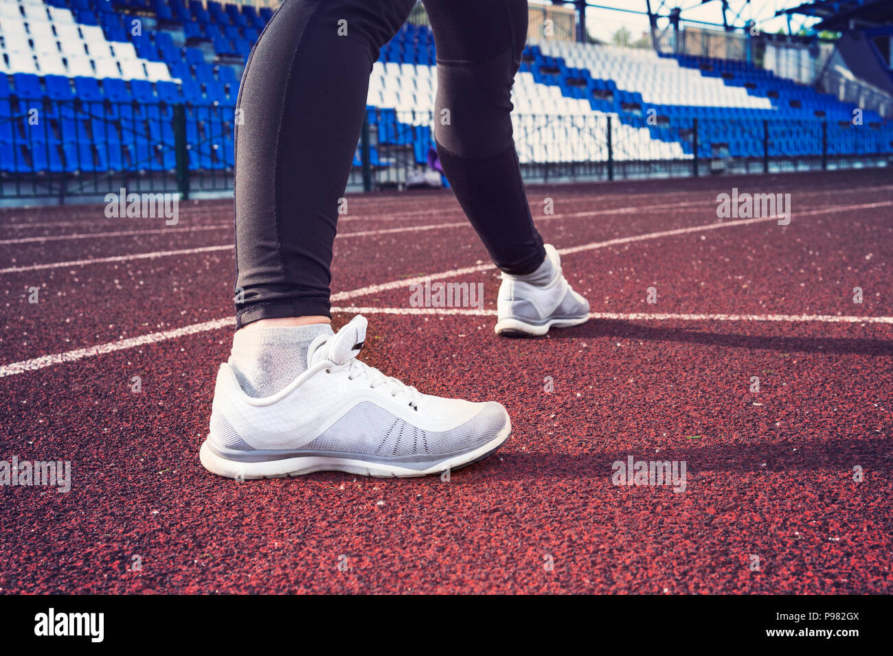 Athlet Frau in laufen, stellen auf der Straße der Stadt. Sport feste Kleidung. Sport Schuhe im Vordergrund, Ansicht von hinten. Stockfoto